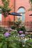 Charming courtyard with vibrant hydrangeas against a classic brick building, featuring stylish outdoor seating and lush greenery.
