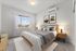 Elegant bedroom with a modern touch, featuring a large window, chic artwork, and stylish lighting. Perfect for relaxation with a cozy atmosphere.