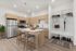 Modern kitchen with sleek light wood cabinetry, stainless steel appliances, and a stylish island, alongside an organized entryway with shelving and hooks.