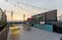 Chic rooftop patio with stylish string lights, vibrant outdoor kitchen, and stunning sunset views over the city skyline.