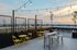 Elegant rooftop terrace with sunset views, featuring chic yellow seating, stylish string lights, and comfortable loungers.