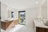 Luxurious bathroom featuring elegant wood cabinetry, dual sinks, and stunning city skyline views through a large window.