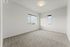 Bright and spacious bedroom with large windows offering panoramic views and plush carpeting.