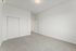 Bright and spacious empty bedroom with plush carpeting, featuring a large closet with sliding doors and a modern overhead light fixture.
