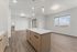 Modern open-concept kitchen and living area with sleek flooring, ample natural light, and stylish pendant lighting.