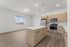 Modern kitchen with sleek stainless steel appliances, spacious island, and elegant pendant lighting, offering a bright and inviting atmosphere with large windows and natural wood cabinets.
