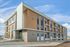 Modern three-story apartment building with stylish wood paneling and sleek balconies, set against a vibrant blue sky.