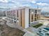 Modern three-story apartment building with a sleek design, featuring private balconies and scenic mountain views under a bright blue sky.