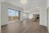 Modern open-concept apartment with sleek wooden flooring, a stylish kitchen island, and large windows offering scenic balcony views.