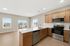 Bright, modern kitchen with stainless steel appliances, sleek wooden cabinets, and an open dining area with scenic views.