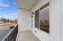 Charming apartment balcony with modern railing, overlooking a tranquil suburban landscape under a clear blue sky.
