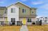Charming two-story townhouse with vibrant yellow doors and modern facade, featuring a welcoming front yard enclosed by a black fence, set in a tranquil neighborhood.