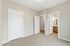 Bright and inviting bedroom with plush carpet, featuring sleek white doors and a modern en-suite bathroom with stylish fixtures.
