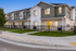 Modern townhouse featuring sleek architecture, vibrant exterior, and charming fenced gardens in a serene neighborhood.