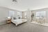 Bright and spacious bedroom with a modern design, featuring a luxurious bed, stylish desk area, and large windows with natural light.