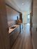 Modern kitchen with sleek wooden cabinetry, stainless steel appliances, and ample lighting leading to a sunlit living area.