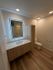 Modern bathroom with elegant wood finish cabinetry, illuminated mirror, and stylish lighting for a luxurious feel.