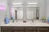 Modern bathroom with double vanity, elegant mirrors, and chic decor including a neon sign and fresh flowers.