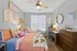 Charming bedroom with vibrant decor, featuring cozy twin beds, a stylish ceiling fan, and a functional study area.