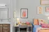 Cozy bedroom with vibrant decor, featuring a stylish desk with modern lamp and playful wall art, perfect for a lively and inviting atmosphere.