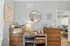Charming workspace with a sleek wooden desk, modern decor, and vibrant art, seamlessly connected to a dining area for versatile living.