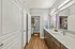 Chic bathroom with a modern double vanity, elegant wood flooring, and vibrant neon wall art for a stylish and inviting atmosphere.