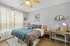 Elegant bedroom featuring a stylish bed with vibrant bedding, a wooden desk with modern decor, and a ceiling fan for comfort.