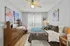 Charming bedroom with modern decor, featuring a cozy bed with stylish linens, vibrant artwork, and a sleek wooden dresser.
