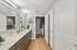 Modern bathroom with dual sinks, large mirrors, sleek cabinetry, and stylish decor on elegant wooden flooring.