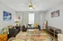 Inviting living room with vibrant decor, featuring a cozy gray sofa, colorful patterned rug, and artistic wall pieces.