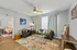 Bright and inviting living room with modern decor, featuring cozy armchair and sofa, artistic wall decor, and vibrant area rug.