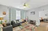 Charming living room with cozy gray sofas, vibrant patterned rug, and stylish decor, highlighted by a chic ceiling fan and warm ambient lighting.