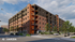 Contemporary apartment building with brick facade and balconies on a bustling city street.