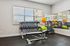 Sleek and inviting fitness room with modern gym equipment, including a bench press, dumbbells, and vibrant exercise balls, illuminated by natural light. | Legacy at Crowley | Atlanta Apartments