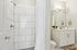 Modern bathroom with sleek tiled shower, elegant vanity with large mirror, and stylish lighting.