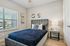 Elegant bedroom featuring a plush velvet bed with decorative pillows, modern wall art, and a stylish nightstand with a contemporary lamp.