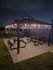 Charming outdoor pavilion with string lights, featuring picnic tables and lush green surroundings, perfect for evening gatherings.