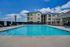 Inviting outdoor pool area with lounge chairs, set against a modern apartment building and vibrant blue skies.