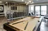 Chic apartment recreation area featuring a stylish pool table, modern seating, and abundant natural light for a perfect entertaining space.