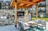 Chic outdoor lounge with a wooden pergola, stone grill area, and comfortable seating, perfect for entertaining in style.