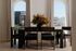 Elegant dining area with modern dark wood furniture, large arched windows, and a vibrant floral centerpiece, offering stunning views of the cityscape.