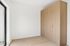 Modern apartment with sleek built-in wooden wardrobe and elegant light-toned flooring, enhanced by natural light from large window.