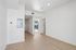 Bright and modern open-concept apartment interior with elegant wood flooring, pristine white walls, and a glimpse of a balcony view.