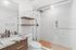 Modern bathroom with elegant marble countertop, wooden vanity, and spacious glass-enclosed shower.