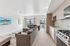 Modern open-concept living space featuring a stylish kitchen, cozy sofa, and a dining area with natural light pouring in through large windows.