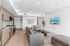 Modern open-concept living area with sleek kitchen, stylish seating, and wall-mounted TV. Bright, inviting space with light wood flooring and tasteful decor.