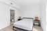 Bright and inviting bedroom with modern furnishings, featuring a cozy bed, stylish side tables with unique lamps, and an ensuite bathroom.