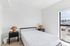 Bright and modern bedroom with minimalist decor, featuring a large window, sleek bedframe, and elegant side tables in a stylish apartment.