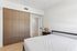Sleek and serene bedroom with modern wardrobe, cozy decor, and bright natural lighting.