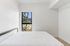 Bright bedroom featuring a large window with scenic views, minimalist design, and fresh white linens.
